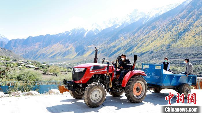 圖為工作人員將把加工完成的糌粑運(yùn)送至村民手中?！〖卫杩h融媒體中心供圖